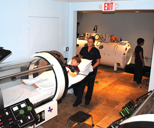 Healthcare worker helping a patient into a hyperbaric chamber